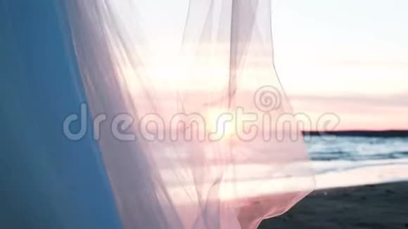日落时透明的布在风中飘动夏日海上风景背景下的婚纱视频的预览图