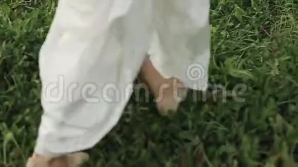 新娘穿着白色长裙走在草地上的特写视频的预览图
