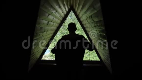 新郎穿上夹克转身走开的剪影从后面看一扇三角形的窗户阁楼视频的预览图