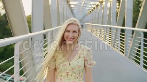 女人回头看桥漂亮的金发女郎回头看镜头一边在桥上奔跑留着波浪发视频的预览图
