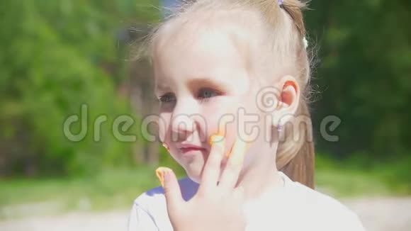 小白种人女孩在夏天的户外用手指画在她的脸上画线视频的预览图