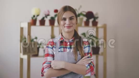 小生意一个穿着条纹围裙和格子衬衫的女孩站在一家花店里双手叠在胸前关于视频的预览图