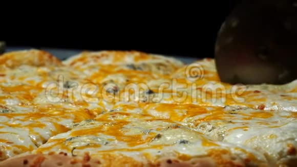 提供美味的四个奶酪披萨和厨师并在桌上的木板上切割披萨片视频的预览图