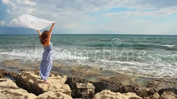 美丽的女人拿着围巾站在岩石上坚强的女人享受自由视频的预览图