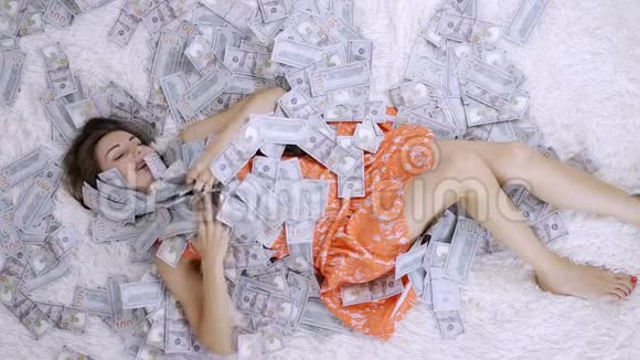 许多钞票在空中缓慢地飘飞一个女孩撒谎很多钱落在她身上幸福的女人快乐视频的预览图