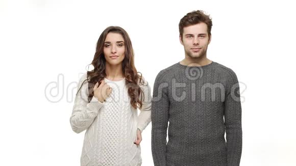 慢动作年轻快乐的夫妇穿着毛衣自然地在白色的背景上微笑视频的预览图