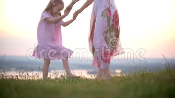 可爱的小女孩在日落时分和妈妈一起跺着脚视频的预览图