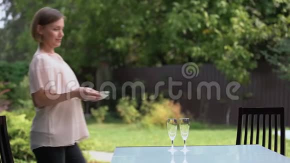 漂亮的家庭主妇提供餐桌等待孩子和丈夫在户外吃饭视频的预览图