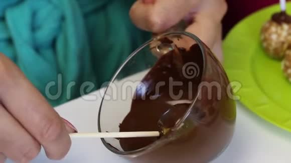 一个女人用融化的黑巧克力蘸了一块饼坯视频的预览图