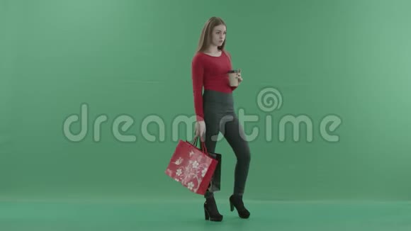 穿着休闲服的漂亮女人正拿着购物袋喝着咖啡或茶她站在一边视频的预览图