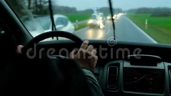 从里面看男人在雨中开车路过模糊的红绿灯视频的预览图