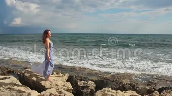 爱的女人站在石头上波涛汹涌的海浪飞溅浪漫的心情视频的预览图