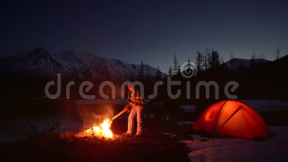 在山上的火边露营的女人视频的预览图
