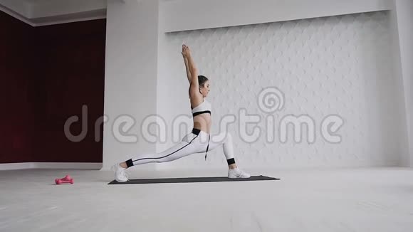 身着白色运动服的美丽少女的侧景在室内做瑜伽或普拉提运动视频的预览图
