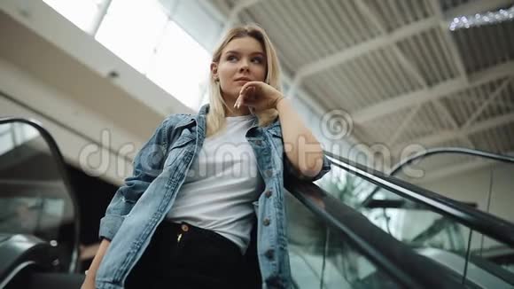 一个体贴的金发女孩走上购物中心的移动楼梯视频的预览图