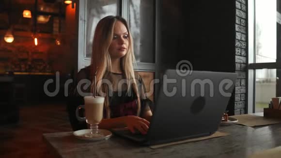 漂亮的时髦女人在咖啡馆里用笔记本电脑视频的预览图