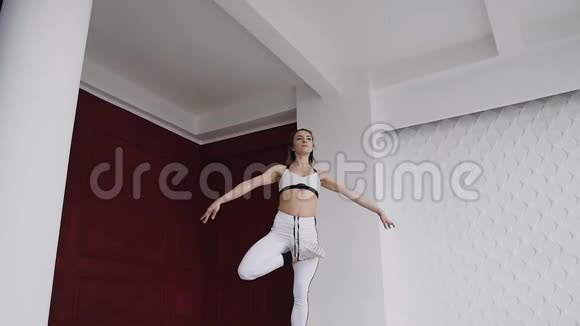 年轻漂亮的白种人女孩在健身房练习瑜伽背景是红白墙健身女孩训练视频的预览图