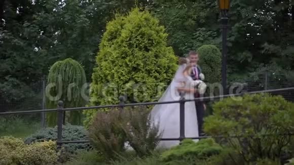 幸福的新婚夫妇相爱是在美丽的盛开的花园里交谈和散步视频的预览图