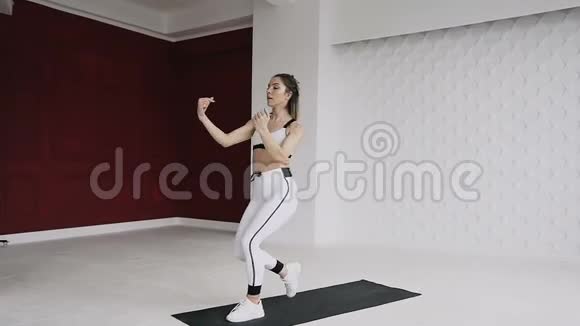 健身美女在晨跑前热身运动女孩在训练前为热身表演跳跃视频的预览图