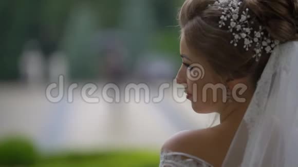 透过优雅新娘的肩膀看着雨中伞下行走的新郎视频的预览图