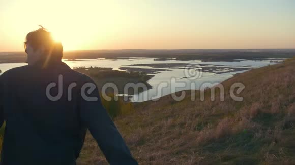 幸福的年轻夫妇在夕阳下牵着手在山上奔跑视频的预览图