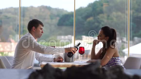 在豪华餐厅约会的漂亮年轻夫妇那个优雅的人正在酒杯里倒红酒视频的预览图