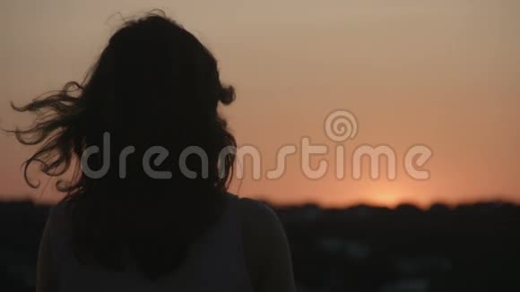 风中拿着围巾的女人剪影看日落日出自由视频的预览图