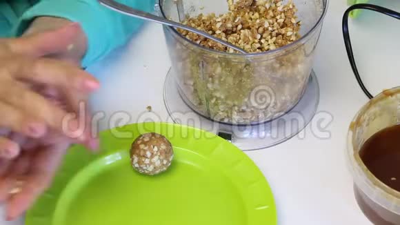 一个女人用滚球来装蛋糕然后放在盘子里从粉碎的花生和其他成分混合视频的预览图
