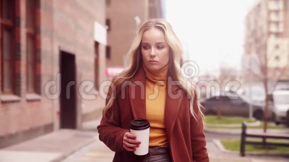 时髦的女人走在街上手里拿着一杯咖啡视频的预览图