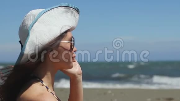 在海滩上兴奋的年轻女子在电话上情绪化地交谈挥舞着双手微笑着视频的预览图