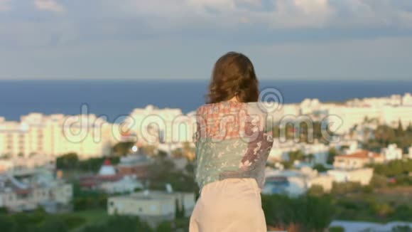 裹着围巾的悲伤女人看着海滨小镇美丽的风景神奇的时刻视频的预览图