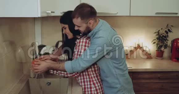 可爱的一对夫妇开始一起在厨房准备晚餐他们正在和每一个微笑在一起玩耍视频的预览图