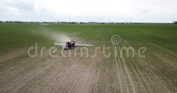 农用拖拉机耕田喷洒的鸟瞰图视频的预览图