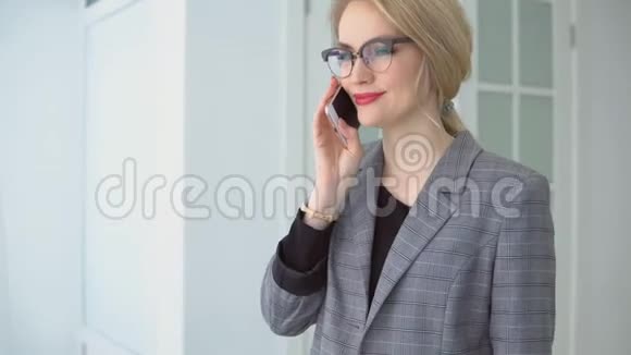 穿着灰色夹克的年轻女子在电话里微笑着视频的预览图