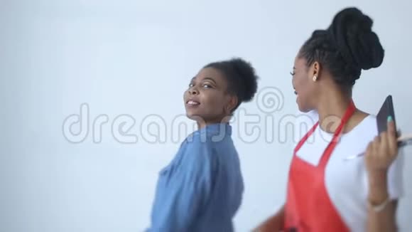这位迷人的非洲模特和她的非洲化妆师在准备拍摄做好准备的同时笑着玩着视频的预览图