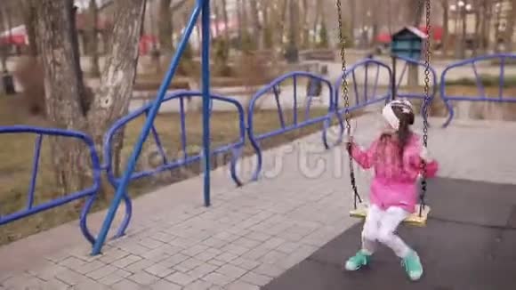 公园里的一天一个小女孩骑在秋千上快乐地笑着视频的预览图