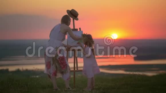 日落时分母亲和女儿的后景描绘了山上的景色视频的预览图