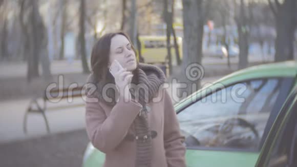 一位中年妇女在汽车附近打电话视频的预览图