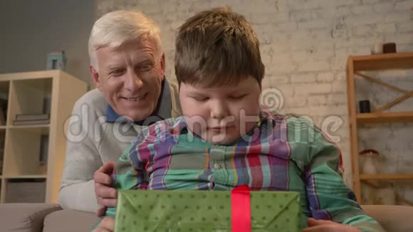 祖父给他孙子一份礼物老人送礼物给胖孩子快乐惊喜快乐情感视频的预览图
