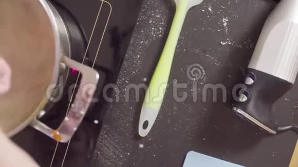 一只糖果手把融化的糖和牛奶混合在锅里视频的预览图