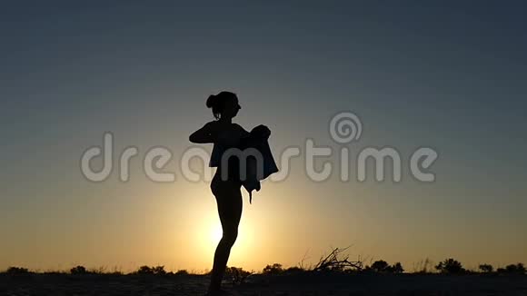 日落时分年轻女子用毛巾裹住自己的身体视频的预览图