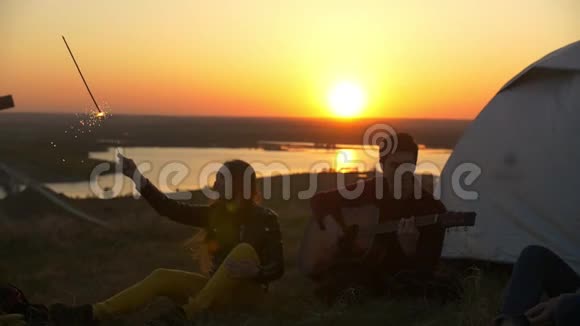 快乐的年轻朋友一起玩在山上日落时弹吉他视频的预览图