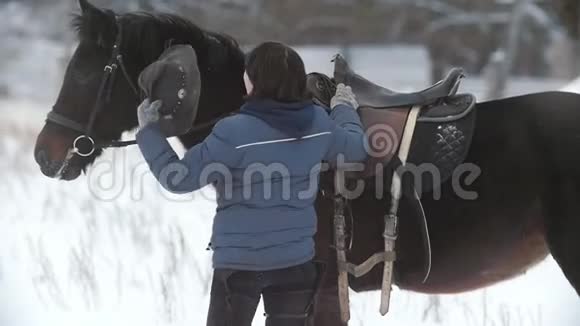 冬天的田野里女人在马旁边戴帽子视频的预览图