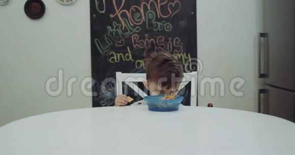 可爱的小男孩坐在桌子旁拿着棒棒糖躲在盘子后面红色史诗视频的预览图