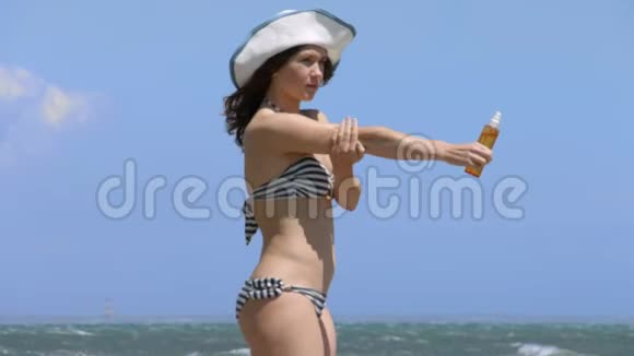 穿比基尼的年轻女子在海边的海滩上晒太阳在身上涂上防晒霜视频的预览图