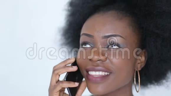 年轻迷人的非洲女人的肖像带着美丽的微笑在手机上用白色的背景说话视频的预览图
