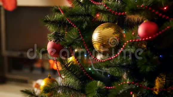 特写4k镜头美丽的金色和红色的子挂在圣诞树上装饰着五颜六色的灯光视频的预览图