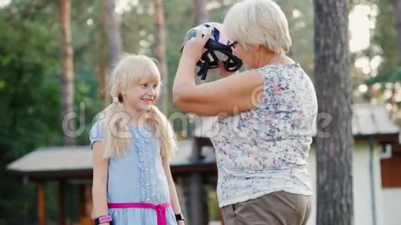 年长的女人为她6岁的女儿戴了一顶防护头盔照顾和保护父母概念视频的预览图