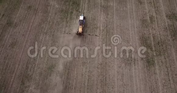 农用拖拉机耕田喷洒的鸟瞰图视频的预览图