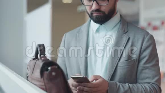 有胡子的人眼镜掉了头看着智能手机视频的预览图